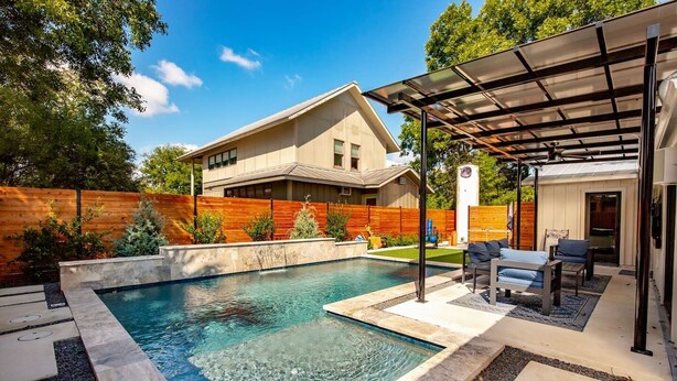 Una casa moderna con piscina, muebles de jardín y una zona de estar cubierta al aire libre.