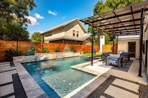 A modern house with a swimming pool, patio furniture, and a covered outdoor seating area. - Warm King Wm Getaway | Heated Pool Near Riverwalk (San Antonio)