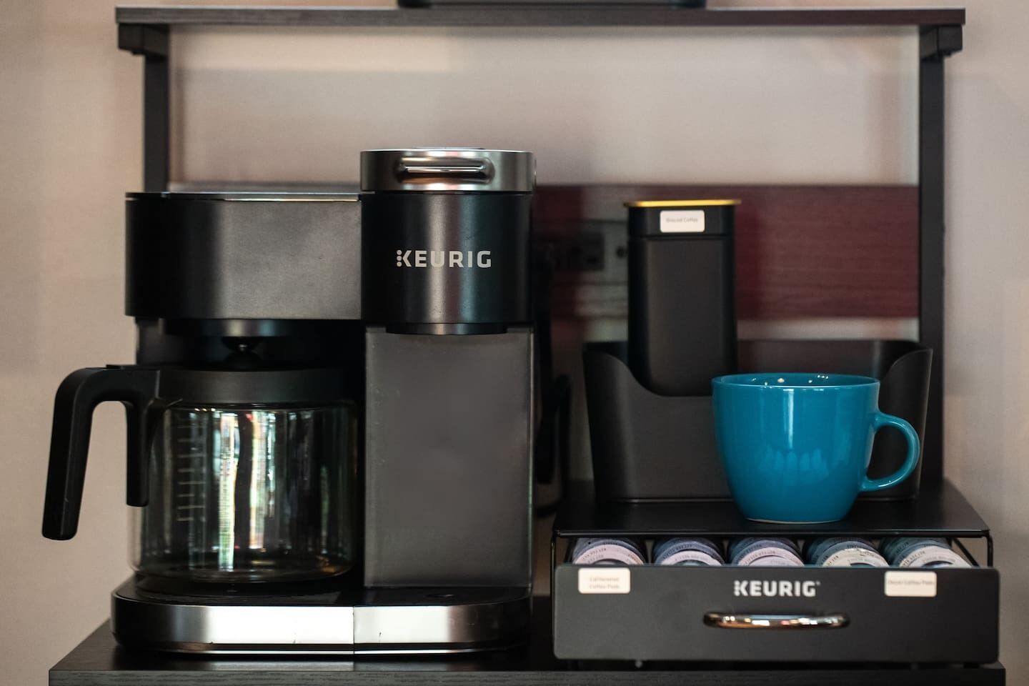 A Keurig coffee maker with a blue mug and a coffee pod holder.