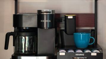 A Keurig coffee maker with a blue mug and a coffee pod holder.