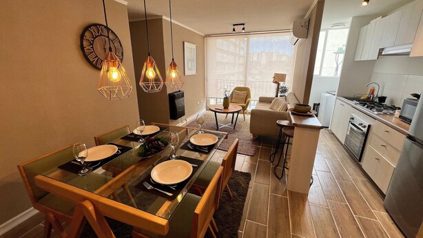 A dining area with a long table, chairs, and hanging pendant lights. - Oceana Suites Bosque Pucalan (Puerto Montt)