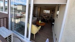 A balcony with a sliding glass door, a dining area with a table and chairs, and a view of the street. - Oceana Suites Bosque Pucalan (Puerto Montt)