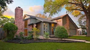 A two-story brick house with a front porch, a garage, and a well-maintained lawn. - Heated Pool | MiniGolf |Arcade| Slide-Family Oasis (San Antonio)