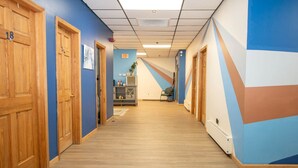 A hotel hallway with wooden doors, blue walls, and a geometric mural.