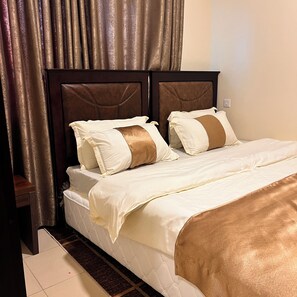 Une chambre d’hôtel avec un grand lit, une tête de lit et un rideau.