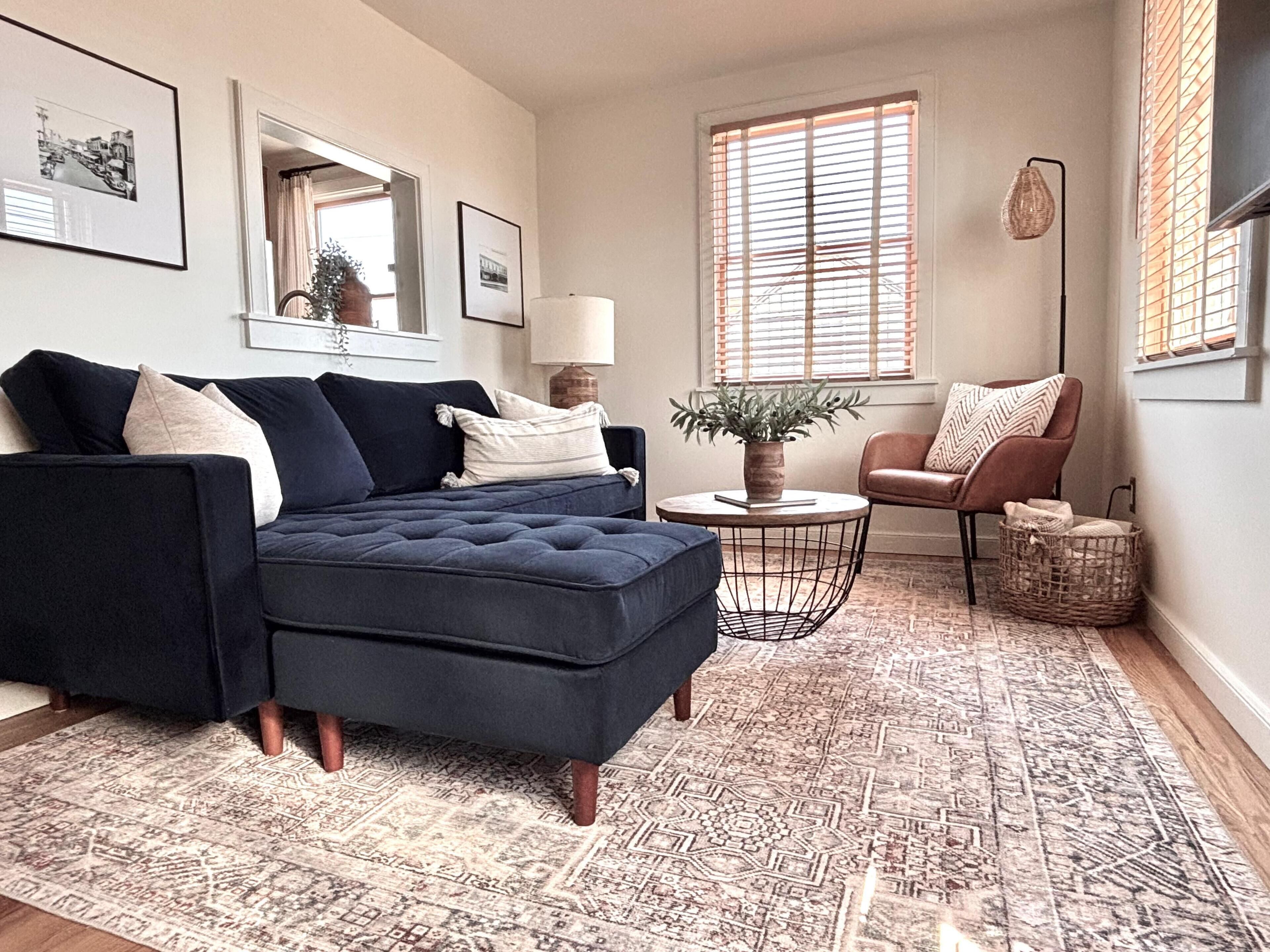 A living room with a sectional sofa, a round coffee table, a side table, a chair, and a patterned rug.