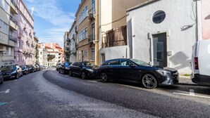 Une rue étroite bordée de voitures garées et d’immeubles à plusieurs étages.