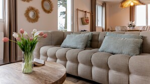 Een woonkamer met een bank, een ronde houten tafel en een bloevas.