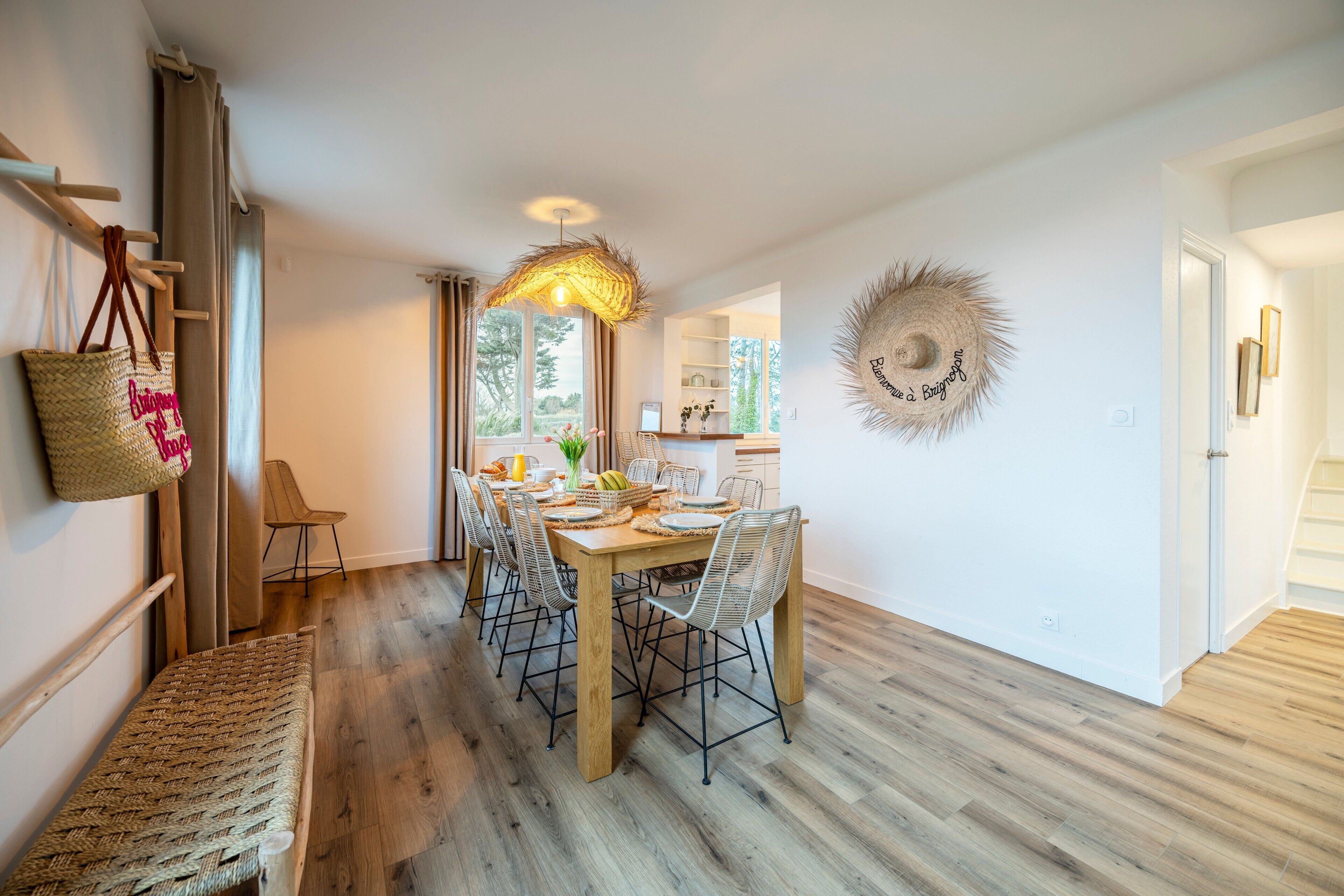Un espace repas comprenant une table en bois, des chaises en métal et un banc en osier.