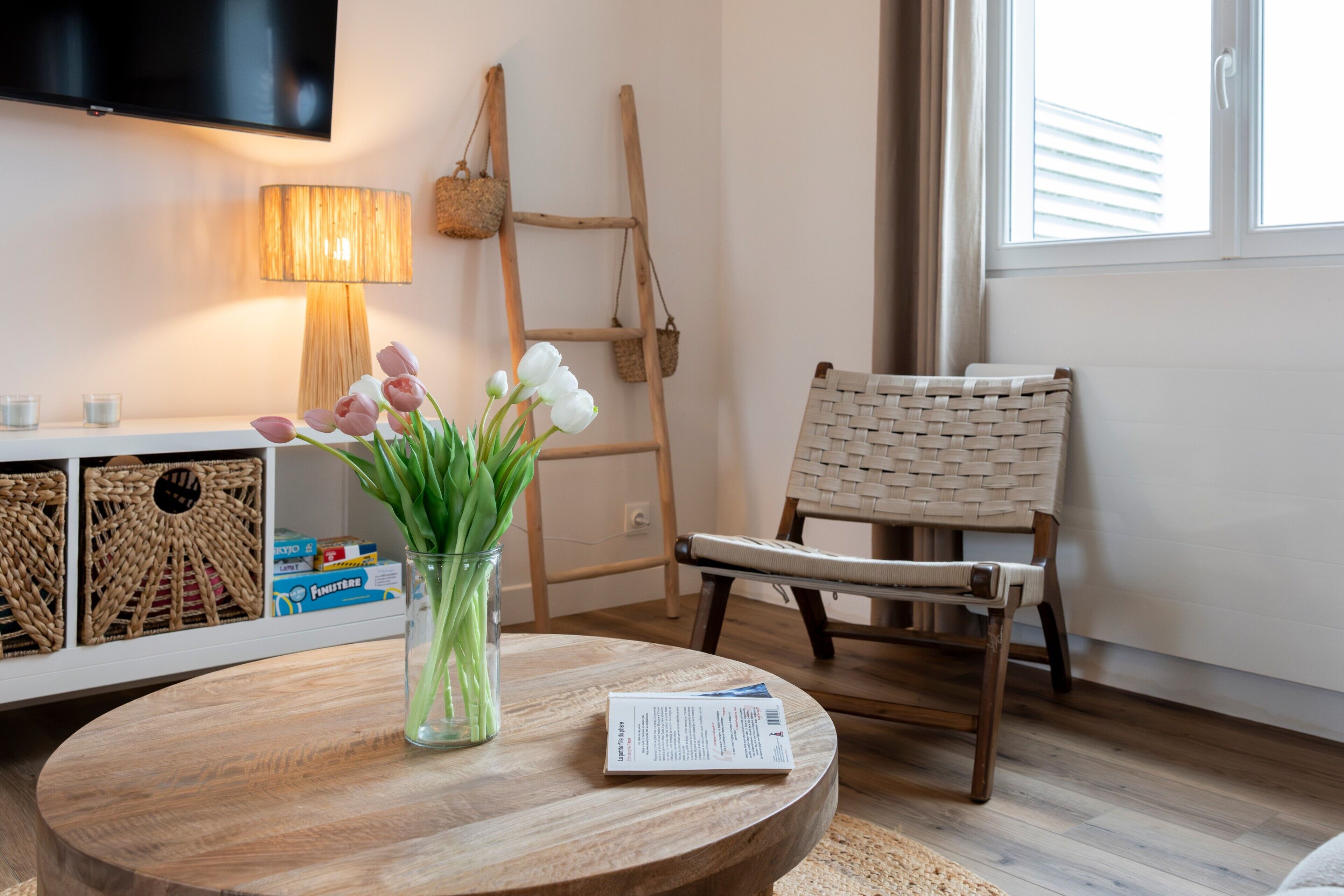 Une table ronde en bois, ornée d’un vase de fleurs, d’une lampe et d’une chaise.