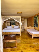 Quarto com uma cama de madeira, uma cama menor, uma mesinha de centro de madeira e um quadro na parede.