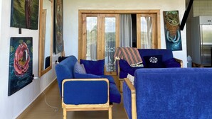 Ein Wohnzimmer mit blauen Sofas, Holzmöbeln und Kunstwerken an den Wänden.