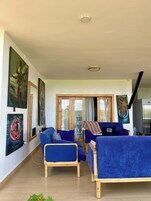 Uma sala de estar com sofás azuis, móveis de madeira e obras de arte nas paredes.