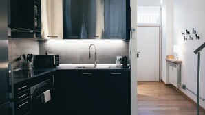 Una cocina moderna con armarios oscuros, un lavamanos de acero inoxidable y un microondas.