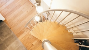 Una escalera de madera con barandilla blanca y una lámpara colgante.