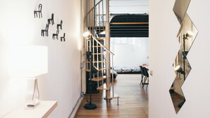 Un interior moderno con una escalera, un escritorio con una lámpara y un espejo de forma original.