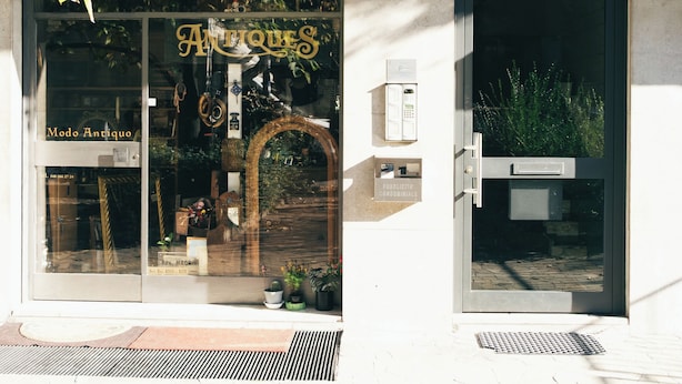 Un escaparate con toldo verde y un letrero que dice 'Antiques'.