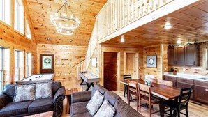 Ein Holzblockhaus-Interieur mit Essbereich im Erker, einer Sitzecke, einem Billardtisch und einer Küche.