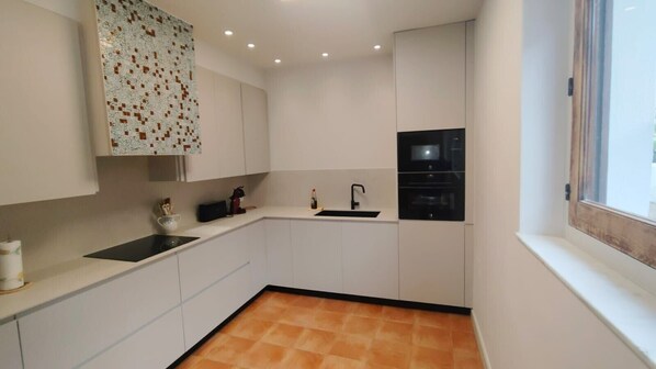 A compact kitchen with white cabinets, a black countertop, a sink, and a microwave.