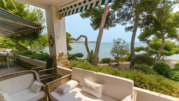 A balcony with a wicker sofa, a small table, and a chair. - Seafront Chalet with Pool, Outdoor Kitchen, Spacious Garden and Stunning Views (Alicante (Alacant))