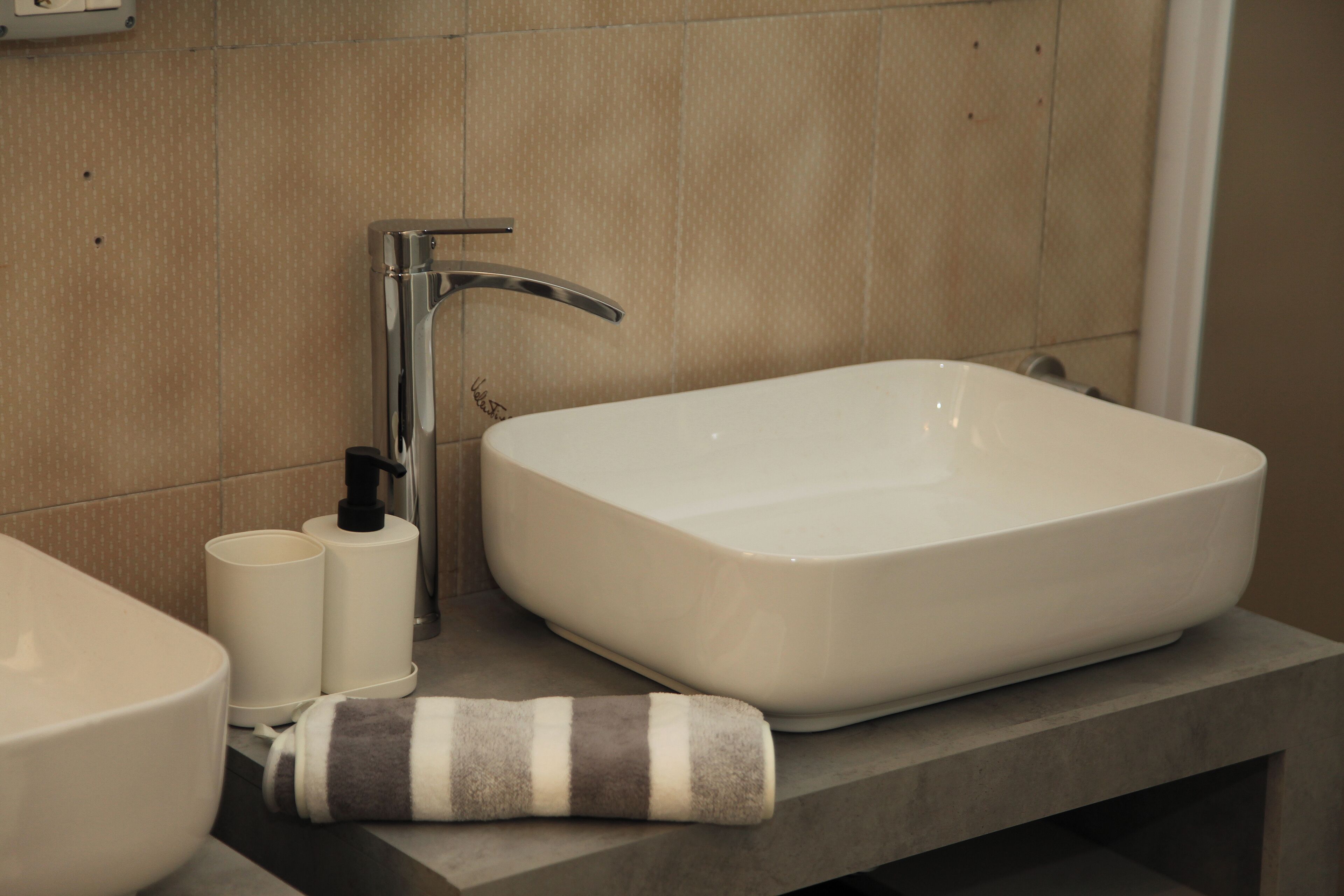 A bathroom with a large rectangular sink, a modern faucet, and a striped towel on the counter.