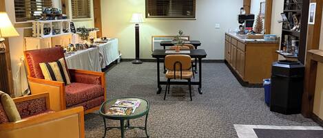 A cozy living area with a ceiling fan, a dining table, and a kitchen area with a refrigerator and a coffee machine.