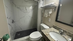 A bathroom with a shower, toilet, sink, and mirror. - Econo Lodge St. Petersburg Central (St. Petersburg)