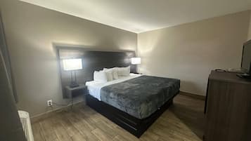 Una habitación de hotel con cama, dos lámparas de noche, un escritorio con ordenador y cómoda.