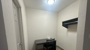 A small, dimly lit room with a single table and chair, a white door, and a ceiling light. - Econo Lodge St. Petersburg Central (St. Petersburg)