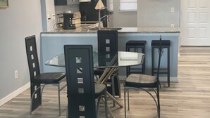 Una cocina moderna con una isla central, sillas negras y una mesa de comedor.