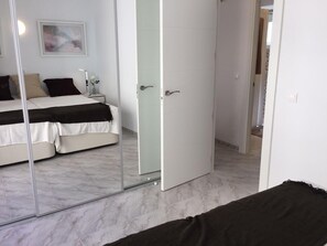 Une chambre à coucher avec un lit, une table de chevet, un miroir et une porte.