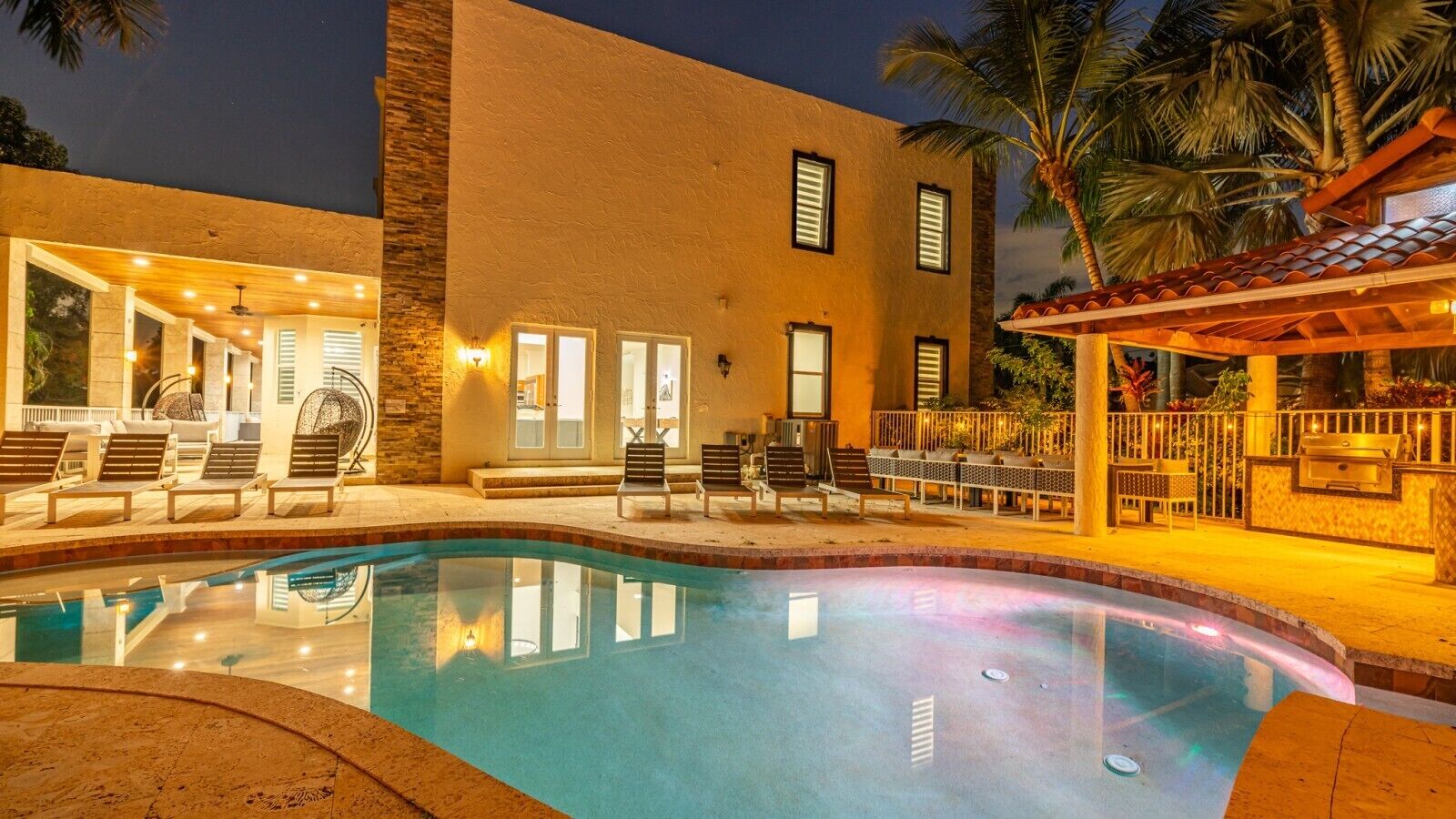 Ein Pool mit Liegestühlen und einer überdachten Terrasse.