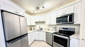 Una cocina moderna con armarios blancos, electrodomésticos de acero inoxidable y una encimera de mármol.