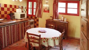 Een keuken met een ronde tafel, stoelen, een magnetron en een koffiezetapparaat.