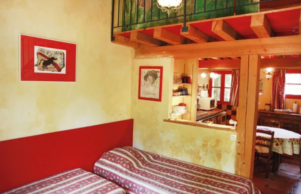 Une chambre avec deux lits, une décoration aux couleurs rouge et blanche, un plafond en bois et une vue sur la cuisine.