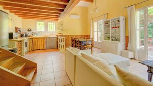 A cozy kitchen with wooden beams, a dining area with a table and chairs, and a sofa in the living room. - Cézanne - Comfort, space and relaxation for families and friends, park view (ARLES)