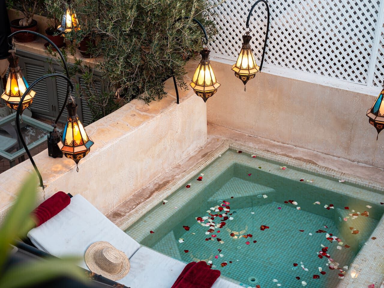 A spa area with a pool, surrounded by potted plants and decorative lighting.