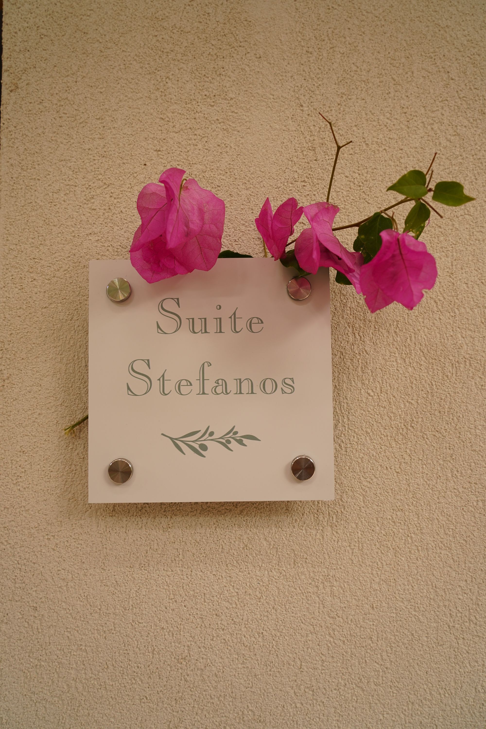 Un letrero con el texto 'Suite Stefanos' sujeto a una pared color beige.