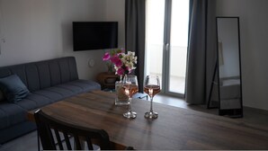 A dining area with a wooden table, two wine glasses, and a vase with flowers. - House of Harmony Suites (Malevizi)
