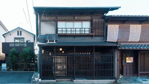 Une maison traditionnelle japonaise, avec une façade en bois, une grande porte coulissante et un petit espace de véranda.