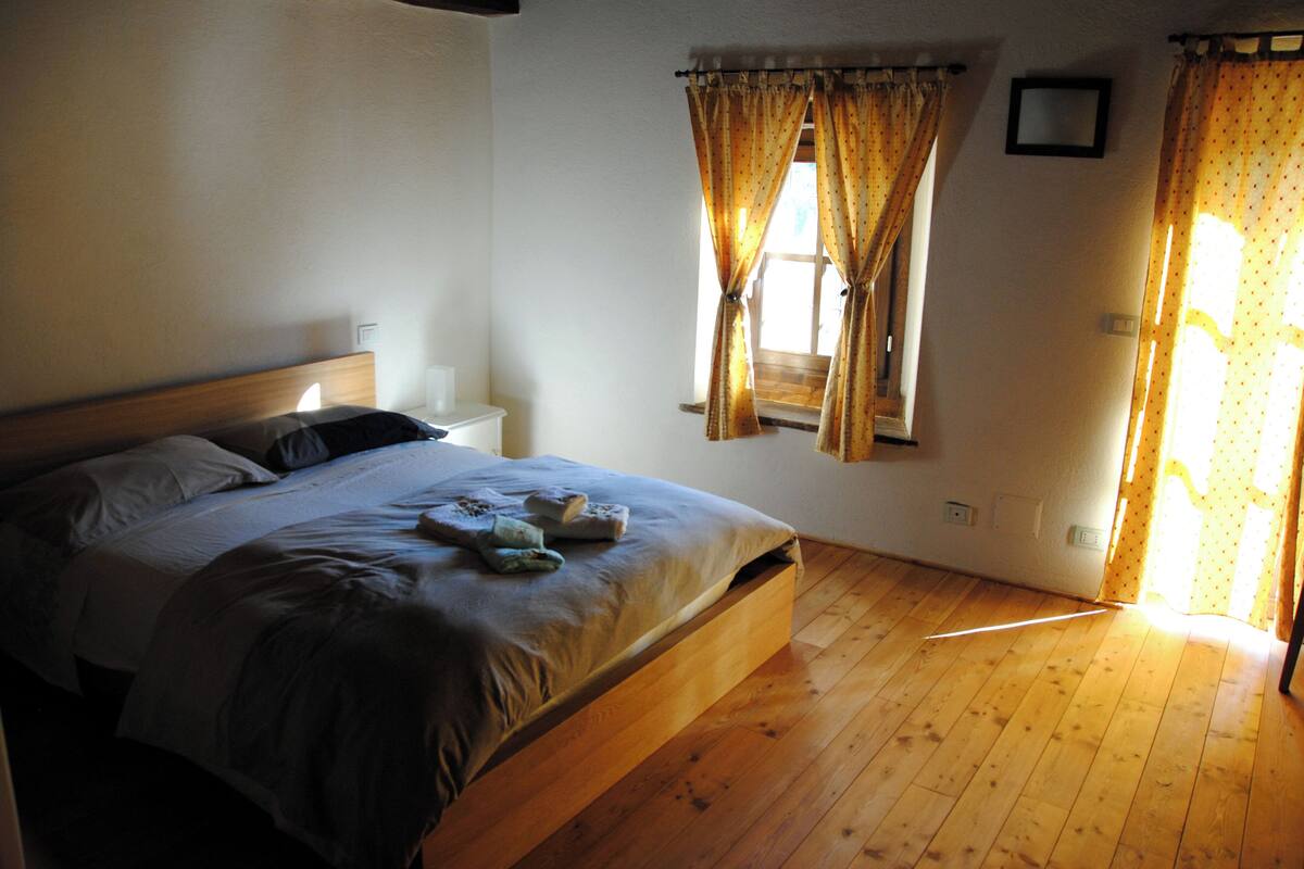 Una camera da letto con un letto di legno, un comodino e una finestra con tende.