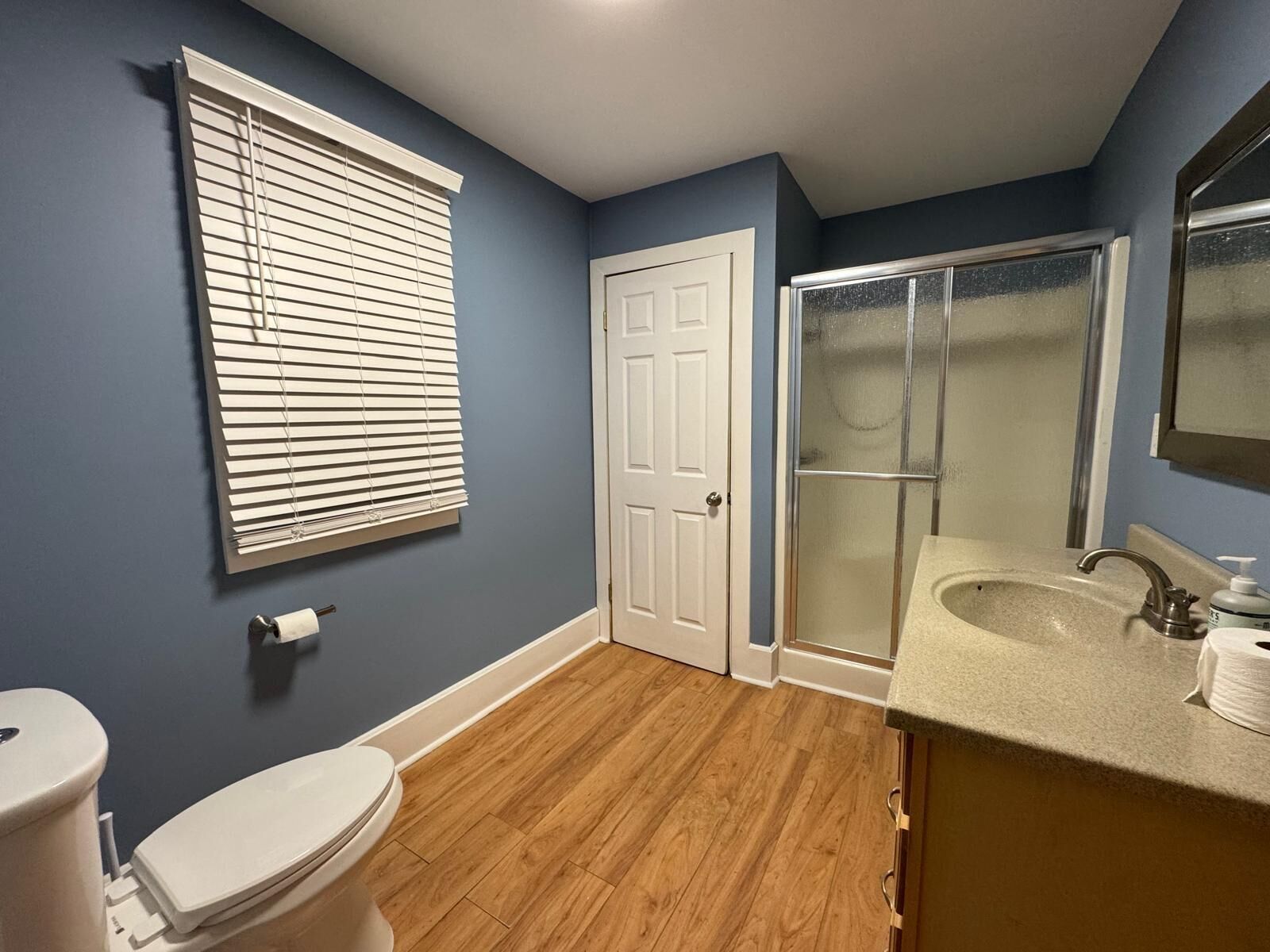 Une salle de bain avec des toilettes, un lavabo, une douche et une porte.