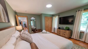 Ett hotellrum med en stor säng, en platt-TV, en garderob i trä, en spegel och utsikt över omgivningarna.