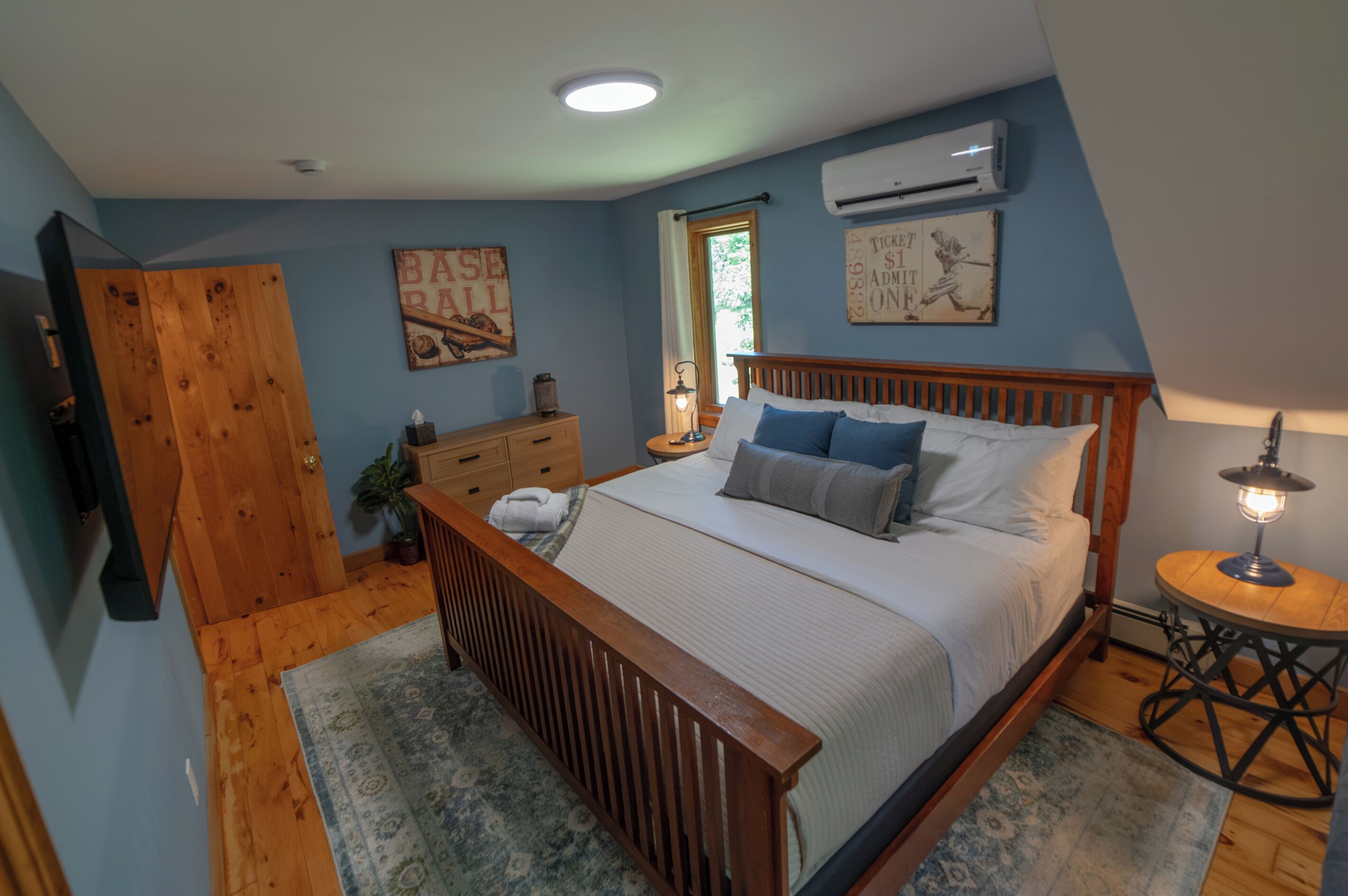 Quarto com cama de madeira, mesa de cabeceira, penteadeira e janela com cortinas.