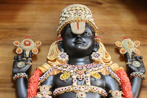 A statue of a deity adorned with intricate jewelry and floral decorations. - Hotel Venkteshwar (Shorapur)
