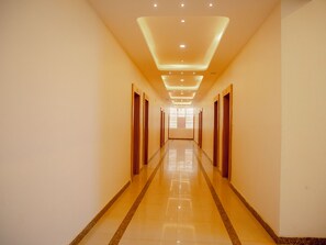 A long, well-lit hallway with a reflective floor and evenly spaced doors. - Hotel Venkteshwar (Shorapur)
