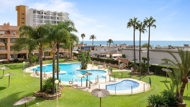 A resort with a central swimming pool surrounded by palm trees and a view of the sea. - RDR516 - Sea View Apartment with Pool in Cala de Mijas (La Cala de Mijas)