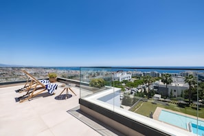 Eine Dachterrasse mit Pool, Liegestühlen und Blick auf die Stadt.