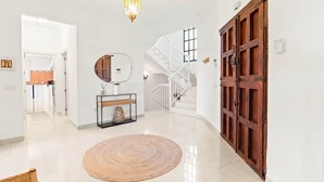 A spacious hallway with a polished floor, a round woven rug, a mirror on a console table, and a wooden door. - RDR461 - Unforgettable Luxury in Marbella Villa (Marbella)
