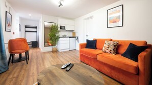 Una sala de estar moderna con una mesa de centro de madera, un sofá naranja y un televisor.